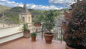 Casa Vacanze Sharazad في Bocchignano: شرفة مع نباتات الفخار وكنيسة