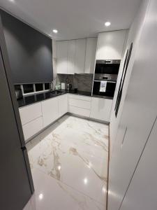 a kitchen with white cabinets and a marble floor at My Home in Braga