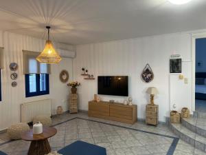 een woonkamer met een flatscreen-tv aan de muur bij Giannis & Maria Sunset House in Lagoúdi Zía