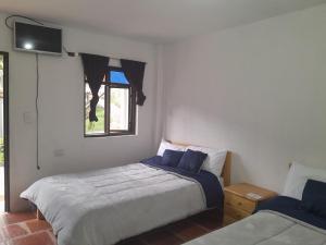 1 dormitorio con 2 camas y TV en la pared en Hotel Mahoma, en El Cocuy
