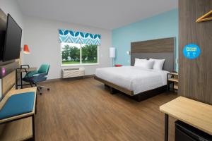 1 dormitorio con 1 cama, escritorio y TV en Tru By Hilton Jacksonville Airport en Jacksonville