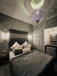 a bedroom with a large bed and a purple chandelier at Essaouira cosy in Essaouira