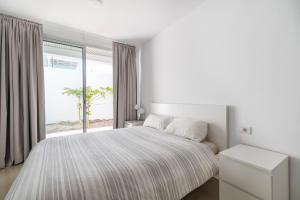 a white bedroom with a large bed and a window at House near the beach w sea view in Arico