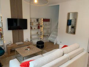 un salon avec un canapé blanc et une télévision dans l'établissement Appart hyper centre Rueil rénové !, à Rueil-Malmaison