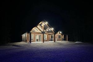 een houten huis met 's nachts verlichting bij The Highmark Cabin in Valemount