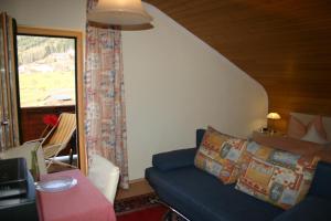 ein Wohnzimmer mit einem blauen Sofa und einem Fenster in der Unterkunft Pension Hoisl in Schönberg