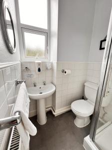 a white bathroom with a toilet and a sink at The Grove in Weston-super-Mare