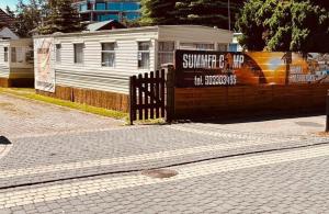 梅尔诺SummerCamp Domki Holenderskie Centrum Mielno 200m do Morza的建筑物前的栅栏上的标志