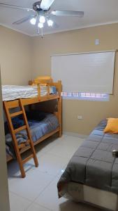 Un dormitorio con dos literas y un ventilador de techo. en departamento 2 dormitorios Cinzano planta baja, en San Juan