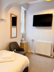 a bedroom with a bed and a chair and a television at The Grove in Weston-super-Mare