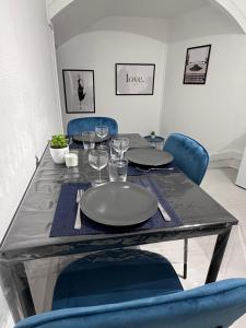 a dining table with blue chairs and a table with plates and wine glasses at L’insolite in Auxerre