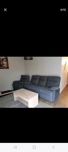 Sala de estar con sofá azul y mesa de centro en Maison rénovée proche circuit des 24H, en Le Mans