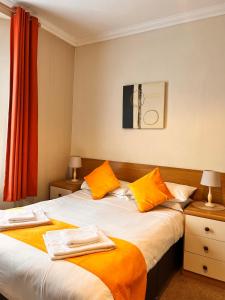 a bedroom with two beds with orange and white sheets at The Grove in Weston-super-Mare