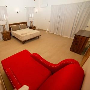 czerwona kanapa w salonie z łóżkiem w obiekcie ωιℓℓу'ѕ νιℓℓα w mieście Jarabacoa