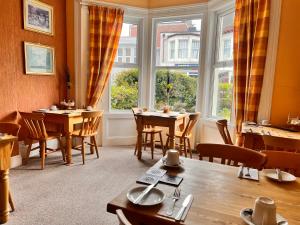 a dining room with a table and chairs and windows at The Grove in Weston-super-Mare
