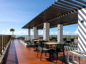 a patio with tables and chairs on a deck at Apart-hotel Beira-Mar em Manaíra in João Pessoa