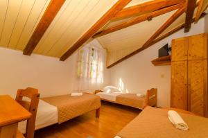 a room with two beds and a window and wooden ceilings at Apartments Verdun in Ivan Dolac