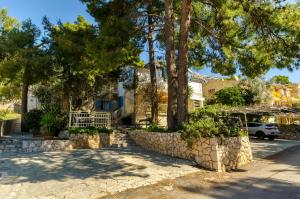a house with trees and a stone wall at Apartments Verdun in Ivan Dolac