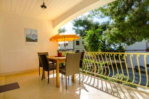 a table with chairs and an umbrella on a balcony at Apartments Verdun in Ivan Dolac