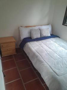 a bedroom with a white bed and a night stand at Hotel Mahoma in El Cocuy