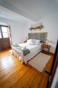 een slaapkamer met een groot bed en een houten vloer bij La bodega D'leti in Jarandilla de la Vera