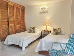 Habitación con 2 camas, silla y lámpara. en Apartamento con salida a la playa en Santa Marta