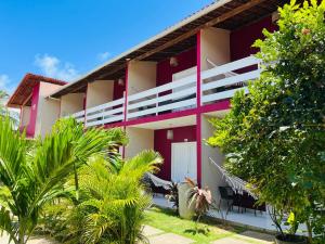 un edificio rojo y blanco con plantas delante en Pousada Maresia, en São Miguel dos Milagres