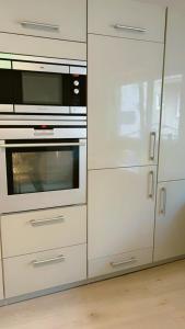 a kitchen with white cabinets and a microwave at hoteliving am Bahnhof in Pohlheim