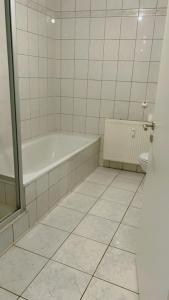 a white bathroom with a tub and a toilet at hoteliving am Bahnhof in Pohlheim