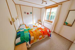 a bedroom with a colorful bed and a window at Chalet Alpenmoos (150m2 - max.11) in Lenk