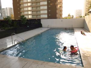 two people swimming in a swimming pool in a building at Dpto. Nuevo y Económico a 20’ del centro in Santiago