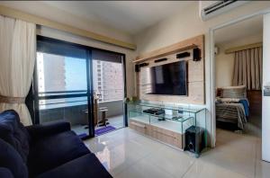 uma sala de estar com uma mesa de vidro e uma televisão em Flat Mar Azul - Beira Mar Fortaleza em Fortaleza