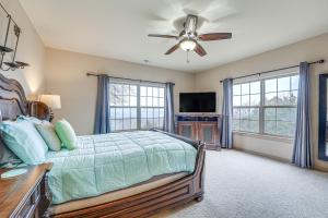 um quarto com uma cama, uma ventoinha de tecto e janelas em Spacious Branson West Retreat Pool and Golf Access! em Branson West