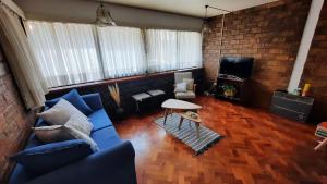 uma sala de estar com um sofá azul e uma televisão em Casa Nevenka em Mendoza
