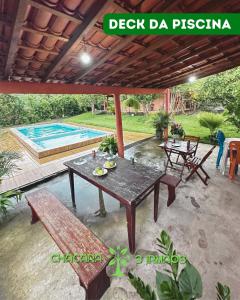 un patio con mesa, bancos y piscina en Chácara 3 irmãos, en Meruoca