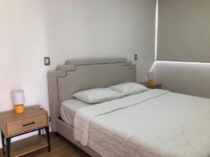 a bedroom with a white bed and a night stand at Impressive City View Apartment A - PH Quartier Marbella in Panama City