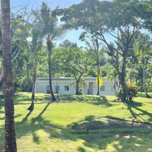 ein weißes Gebäude inmitten eines Parks mit Palmen in der Unterkunft Papaya Casita - On an organic farm in Jamao al Norte