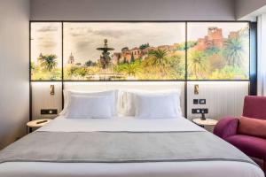 a bedroom with a large bed and a purple chair at Barceló Malaga in Málaga
