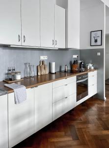 a kitchen with white cabinets and a wooden floor at Stylowy Park Apartment Wawrzyniaka in Wrocław