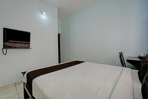 a white room with a bed and a tv on the wall at OYO Flagship 81266 Slv Hotel in Bangalore