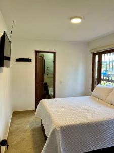 1 dormitorio con cama blanca y baño en Casa Akuaina en Villa de Leyva