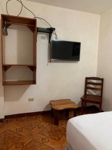 Habitación con cama, TV y silla. en Casa de Huespedes Milena, en Puerto Baquerizo Moreno