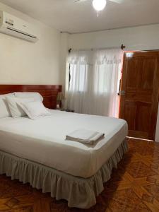 1 cama blanca grande en un dormitorio con ventana en Casa de Huespedes Milena, en Puerto Baquerizo Moreno