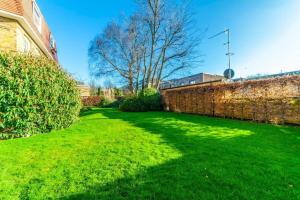 a garden with a brick wall and green grass at Cosy 1-bedroom apartment - Putney High Street in London