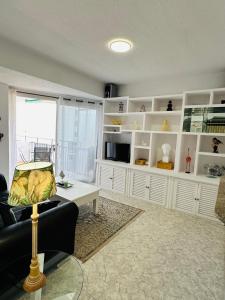 uma sala de estar com um sofá, uma mesa e prateleiras em Apartamentos del Fuerte Marbella - Centro y Playa em Marbella
