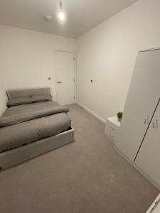 a white bedroom with a bed and a dresser at West Heights SE in Croydon