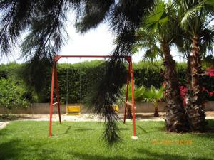 a swing set in the grass next to a palm tree at Chalet in PEÑISCOLA in Peñíscola +1 photo