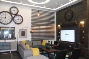 a living room with a couch and a tv and clocks at Villas Libdo Immo in Cotonou