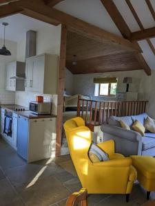 a kitchen and living room with a yellow chair and a couch at Molly's Cottage in Larne