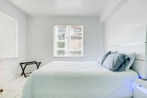 een witte slaapkamer met een bed en 2 ramen bij Amazing apartment in Miami Beach in Miami Beach